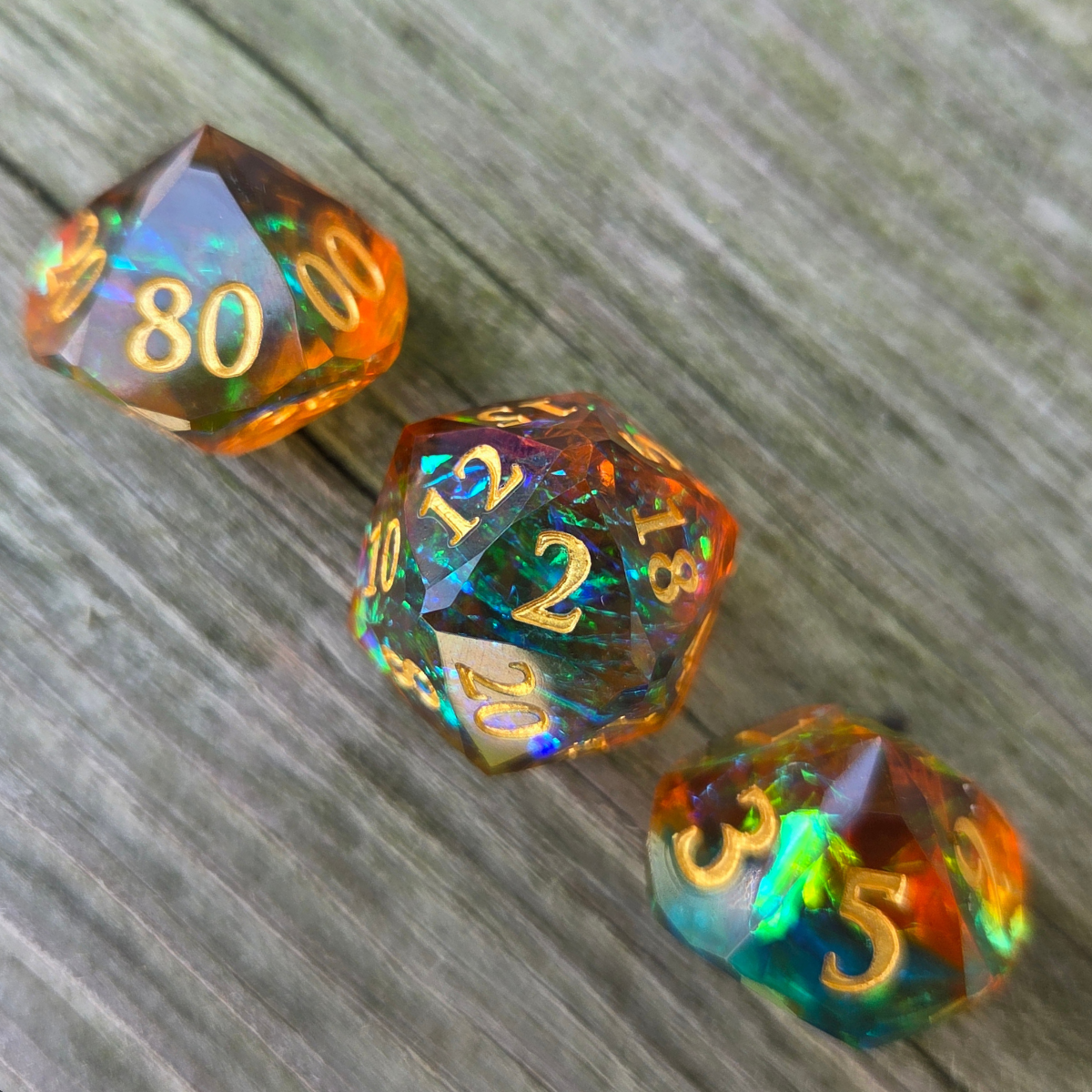 Three multicolored dice with gold numbers on a wooden surface