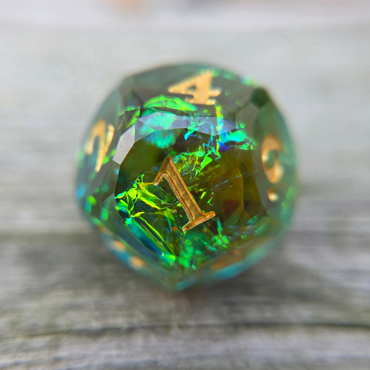 green d12 with holographic foil and gold numbers, sitting on a wooden surface