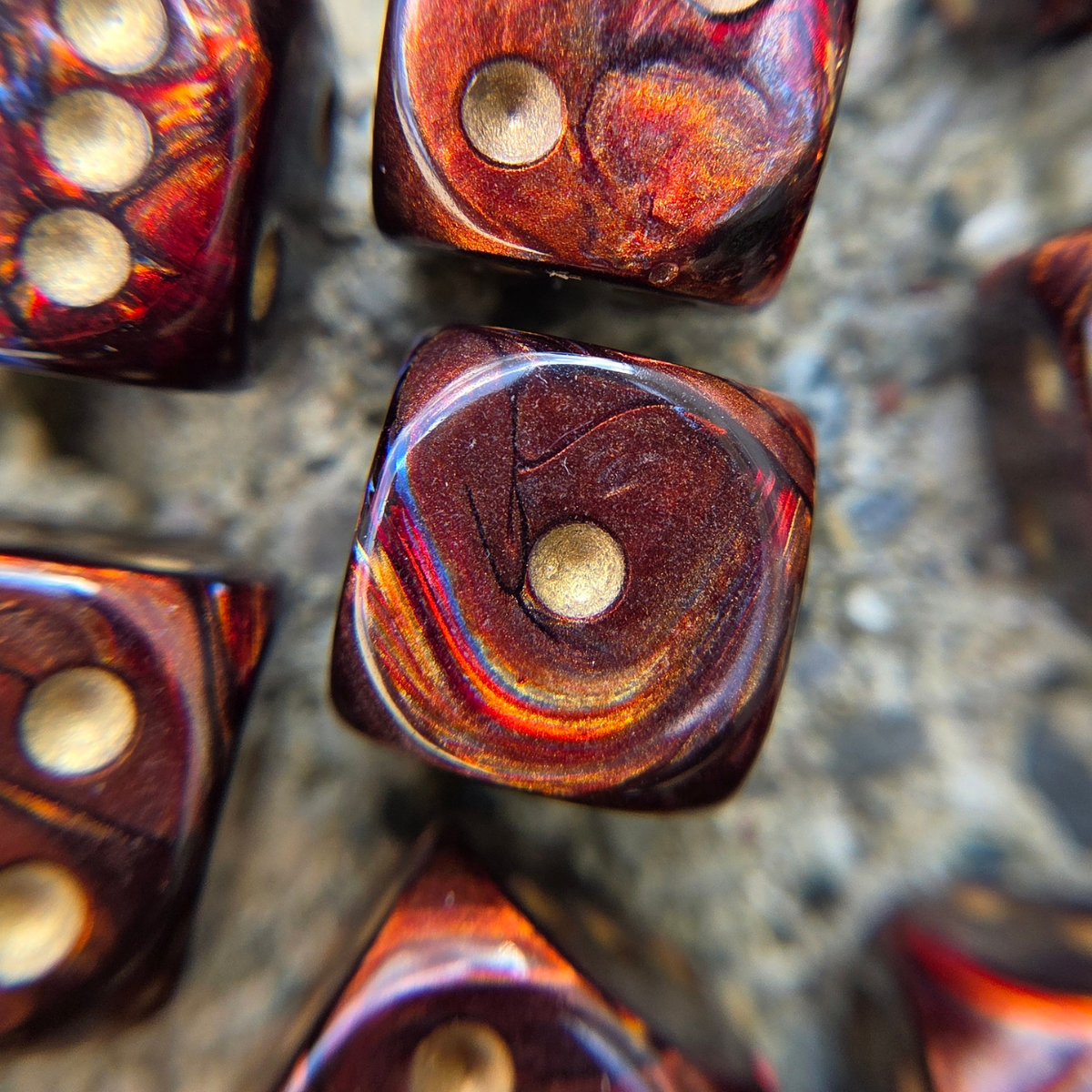 close-up of marbled red, orange, and blue dice with soft golden pips