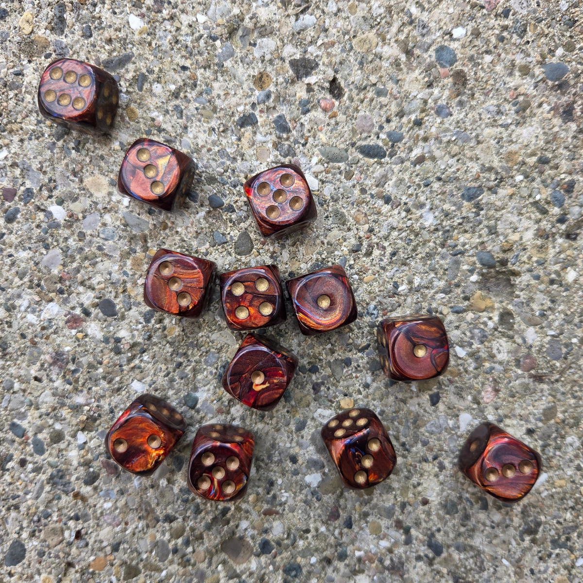 12 marbled red and gold dice on a textured rock