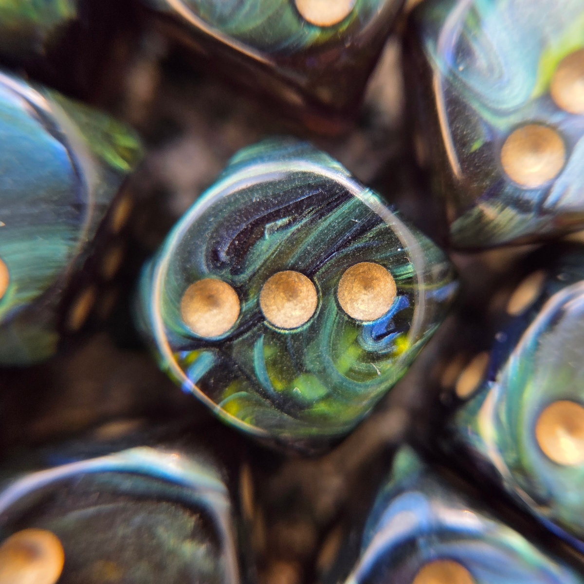 close up of a marbled green six-sided die with golden pips