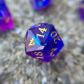 A purple d20 with holographic foil sitting on a concrete background