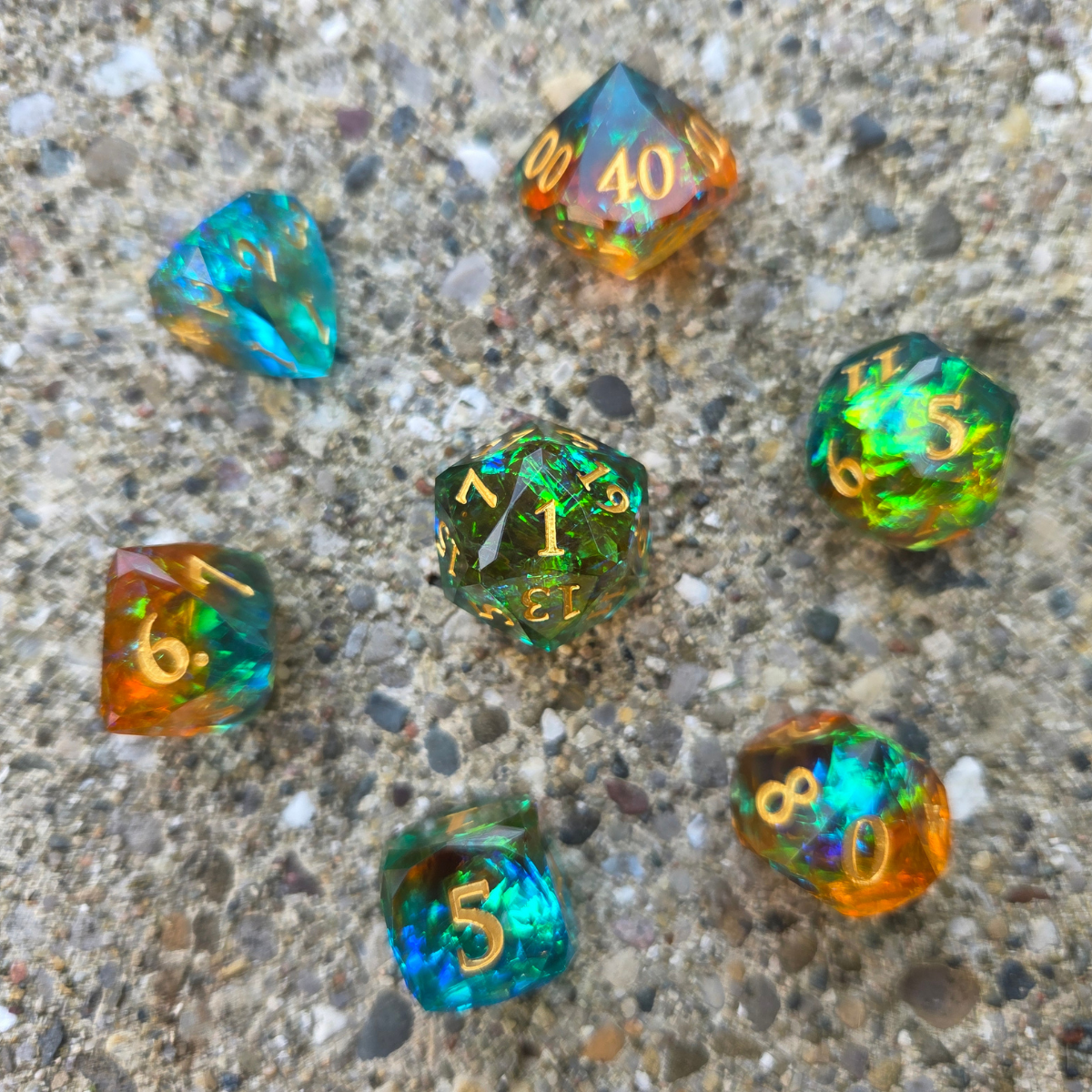 A full set of colorful, blue and orange dice sitting on a concrete surface