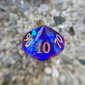 Purple polyhedral percentile die with gold numbers on a blurred natural background