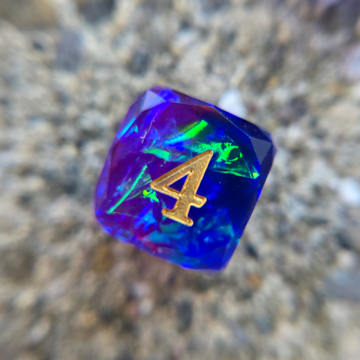 A close up of a purple d6 prominently featuring shimmering, green and blue foils