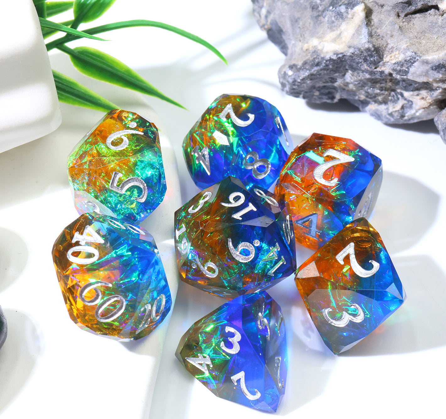 a full set of colorful dnd gaming dice with a small plant in the background