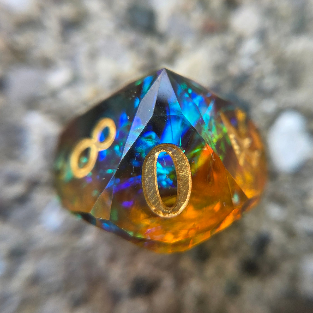 Multicolored d10 featuring a gold number 0