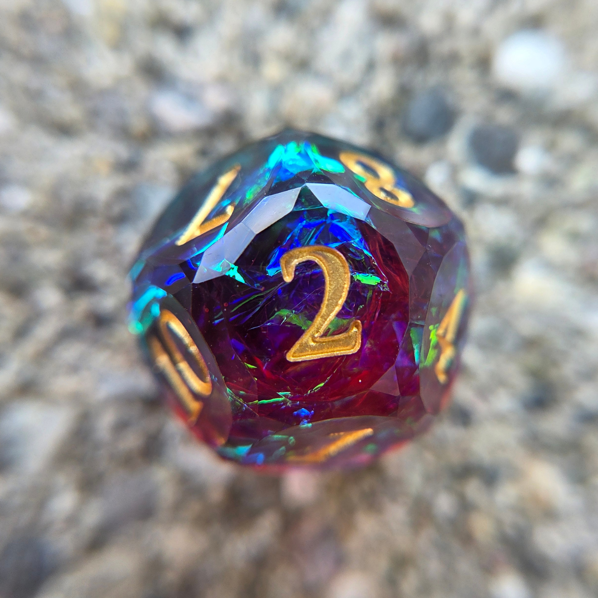 A red and blue die with gold numbers and multicolored holographic foil