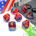 Set of colorful polyhedral dice with numbers on a white surface with a book and stones in the background.